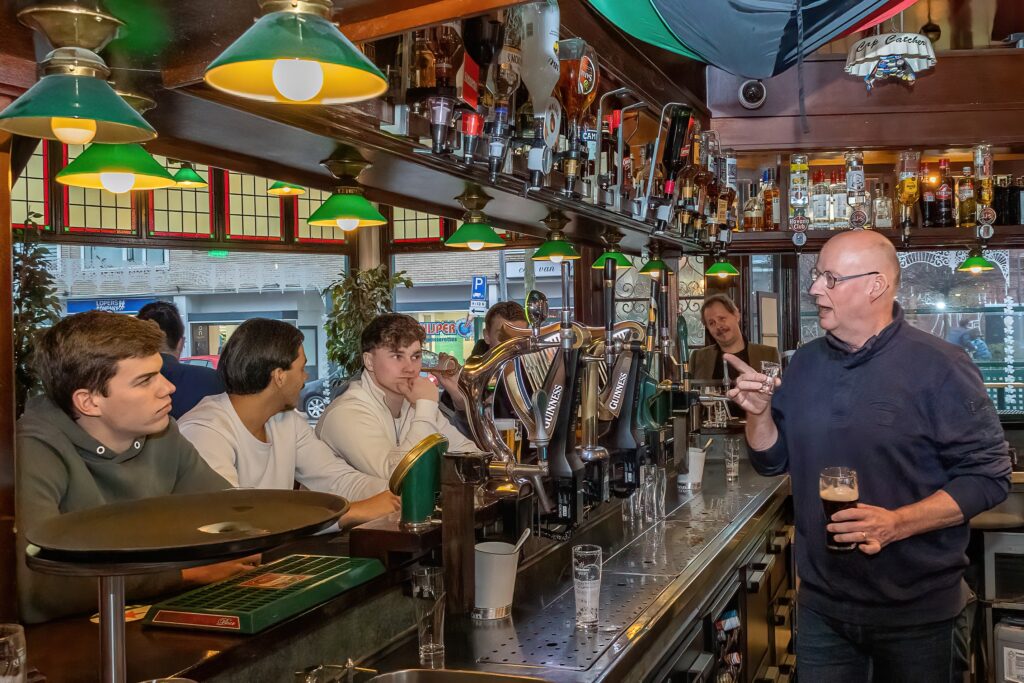 Horecamedewerker adviseert gasten aan tafel over een gerecht tijdens een korte teambriefing in het restaurant